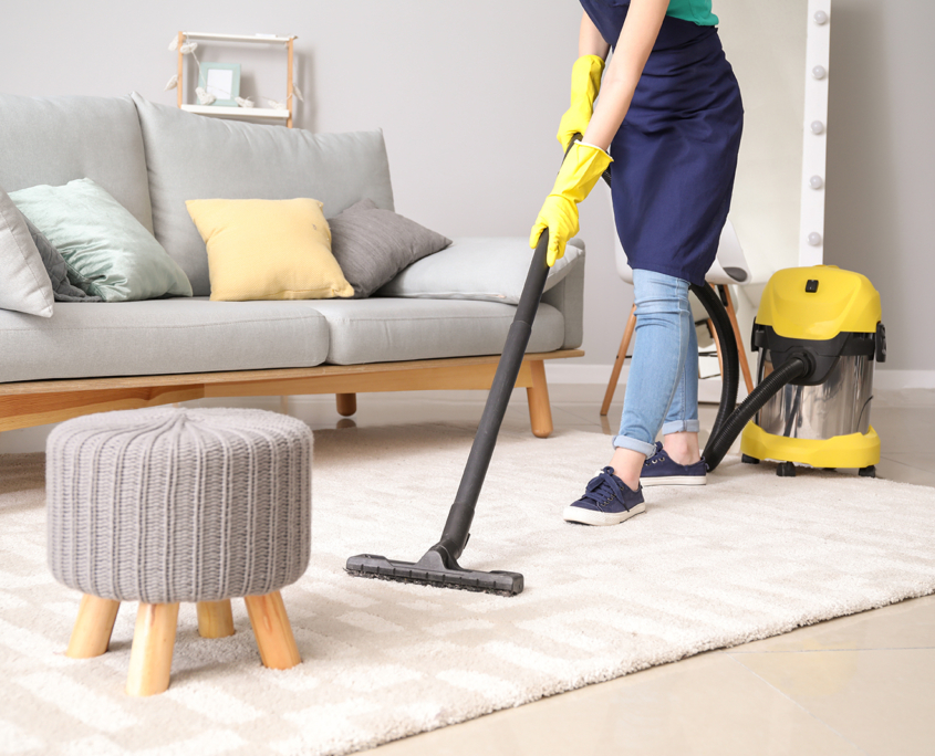 Female janitor with vacuum cleaner in room